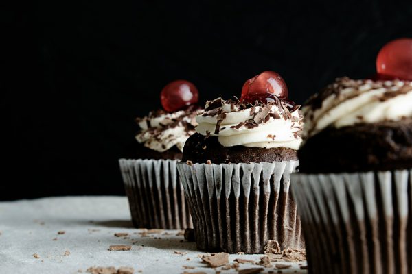 three chocolate cupcakes with cherries