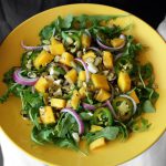 mango salad, hands holding, arugula