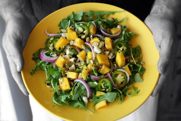 mango salad, hands holding, arugula